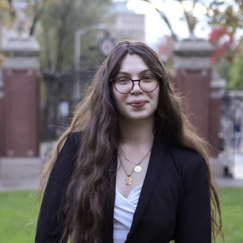 headshot of Razanne Shoukhef standing in front of the Van Wickle Gates at Brown University. 