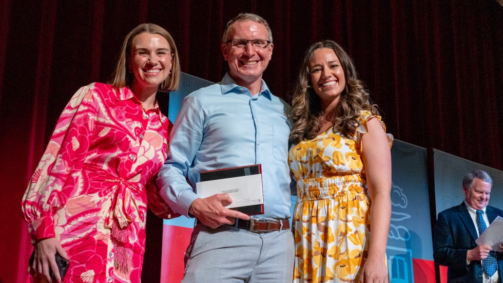 three people standing with award