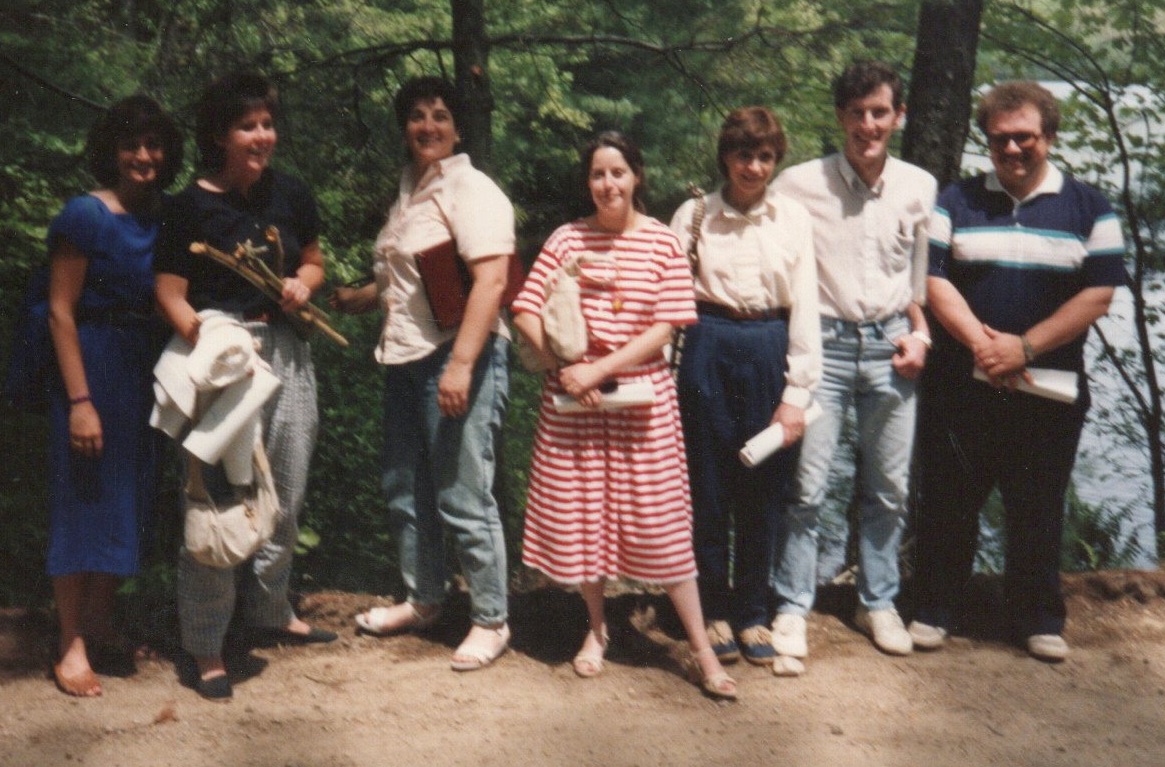 group of people in front of woods and a lake